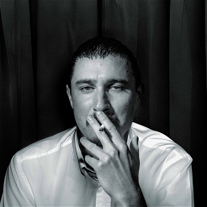 Comedian Tom Rosenthal is smoking in an image this imitates The Arctic Monkeys' debut album cover