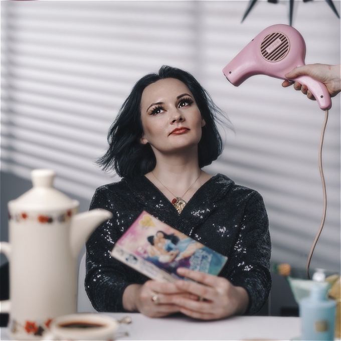 Female comedian with brown hair wearing sequinned jumper