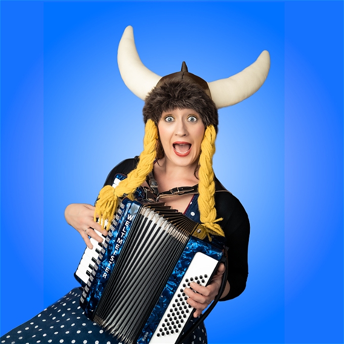 female comedian with pink beehive wig, purple corset, and fuchsia sequin kaftan is reaching toward the camera