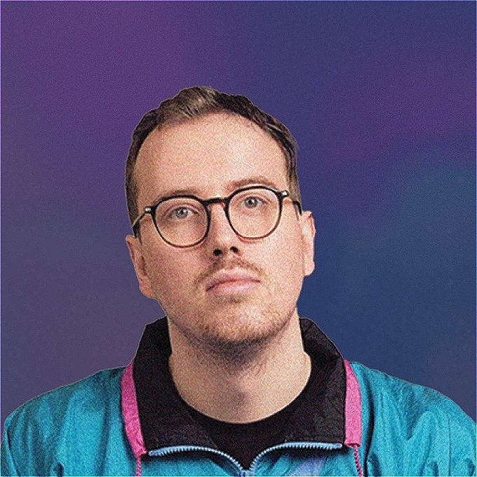 Zoomed in face of Eric with a sideways glance in a pink and blue shell jacket against a blue background.