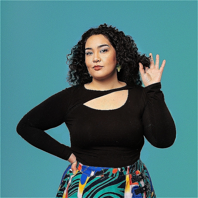 With one hand on her hip and the offer twisting her hair Erika smiles sweetly at the camera