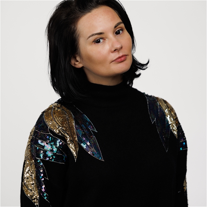 Female comedian with brown hair wearing sequinned jumper