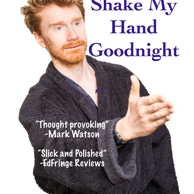 Male comedian with ginger hair, reaches out hopefully to shake someones hand while wearing a dressing gown.
