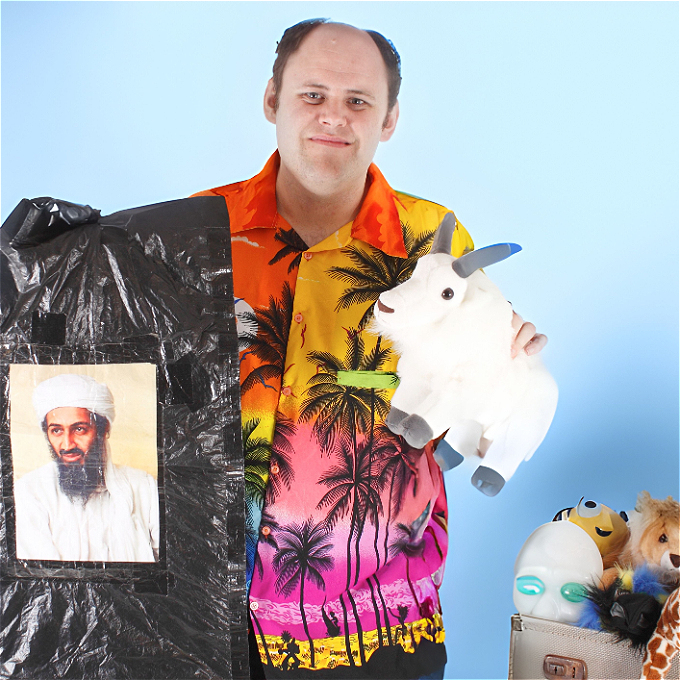 Man in loud shirt, holds up crazy looking props & toys