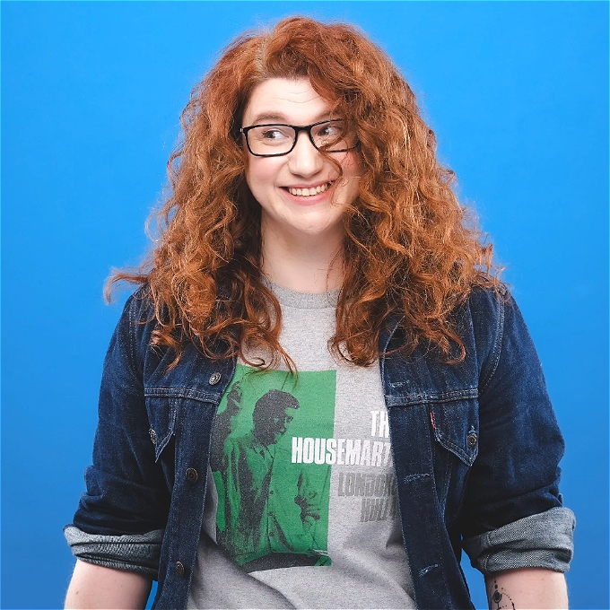 Female Comedia. Red curly hair. Wearing a Housemartins Tshirt
