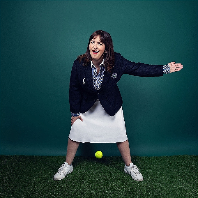 A female tennis line judge smiles wryly as she calls the ball out.