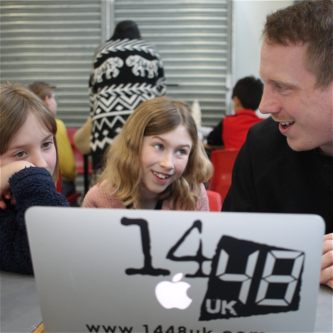 Two children sit a laptop with a male writer