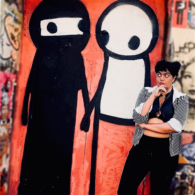 Comic looking up at a stylised graffiti image of a Muslim and someone of another cultural group, could be white and British; but who knows... holding hands.