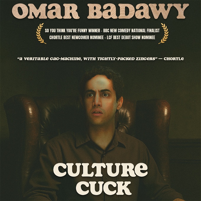 Male comedian sat on leather chair staring into the distance - confused.