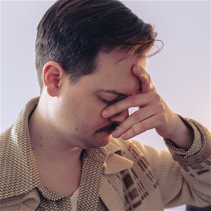 Comedian Andy Barr looks exasperated, head resting in hand