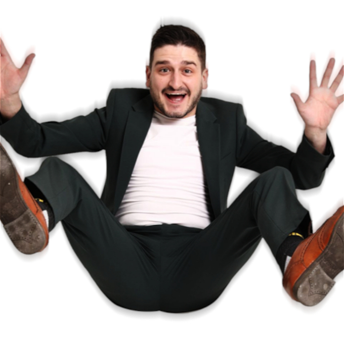 Male comedian with short brown hair and a large smile