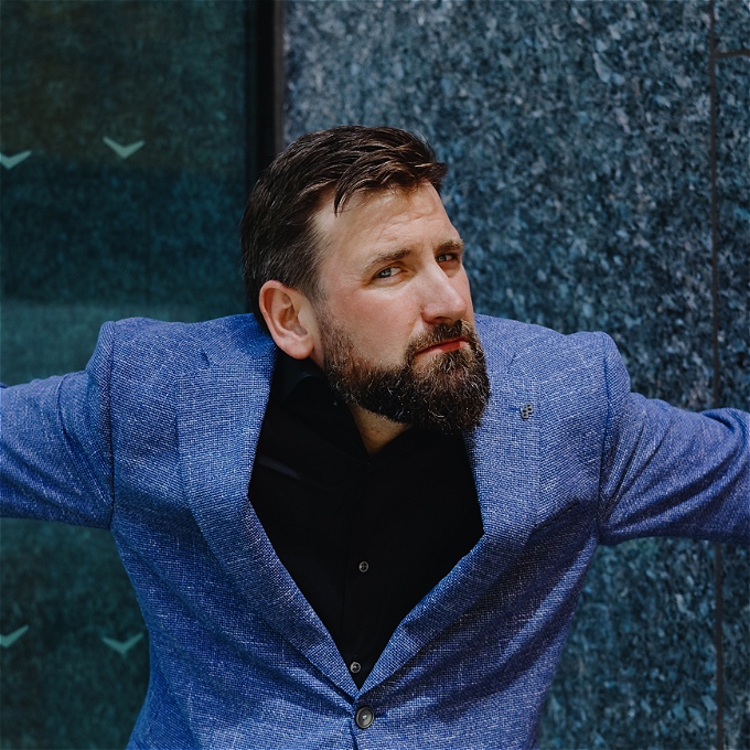 bearded comedian looks vague in a corner