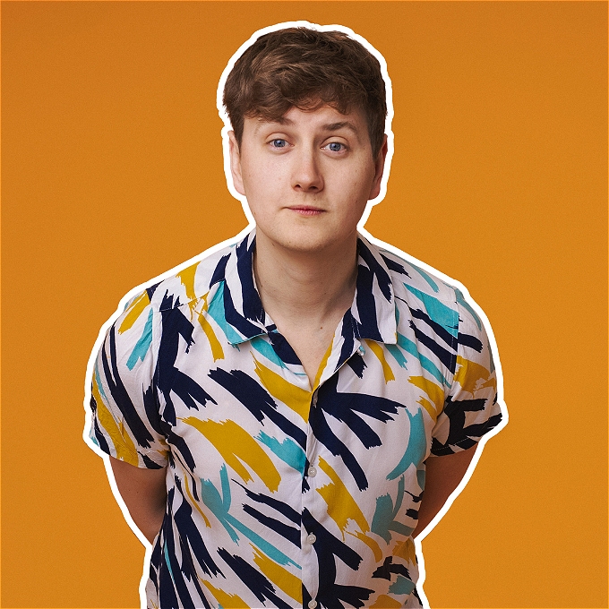 Male comedian (Joseph Emslie) looking at the camera, with an orange background.
