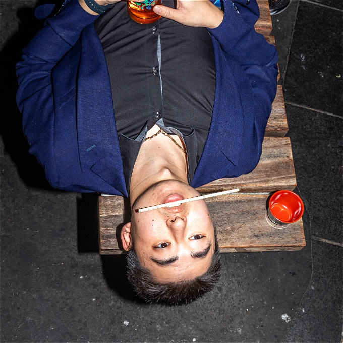 Asian Man upside down with chopstick in mouth