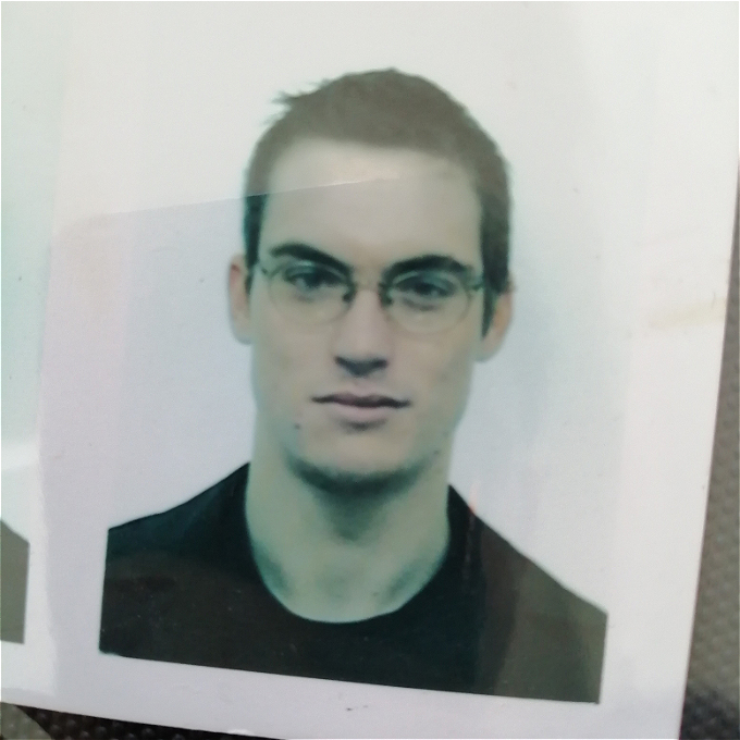 A passport photo of a white male comedian from when he was approximately twenty years younger (in lieu of a proper head shot)
