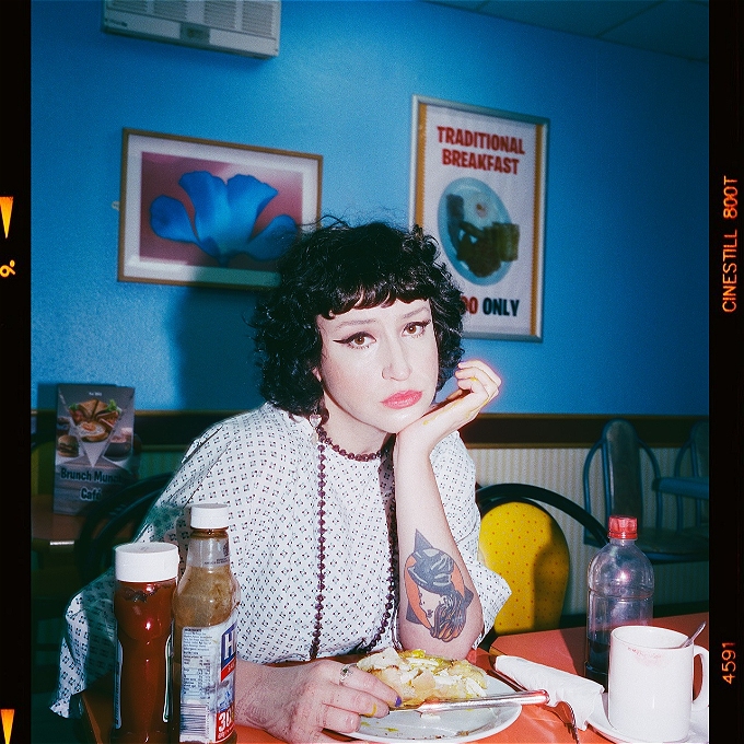 Molly McGuinness sits in a greasy spoon cafe wearing a hospital gown.