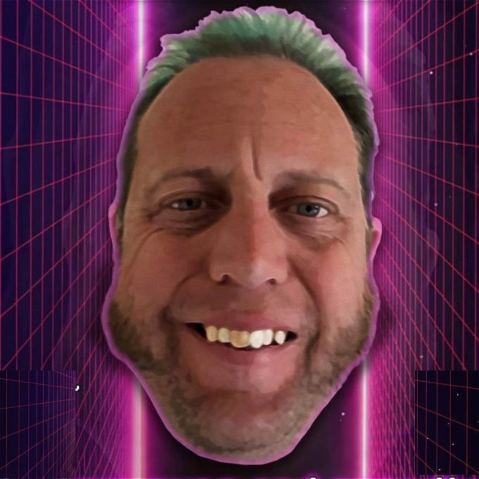 Image is a disembodied head of a white male middleaged comedian with impressive sideburns and green/blue hair. The backdrop is a glowing pink crisscross pattern on a black background, to indicate a computer simulation