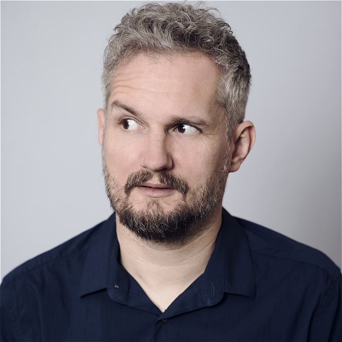 Handsome middle aged comedian looking to the left for some reason