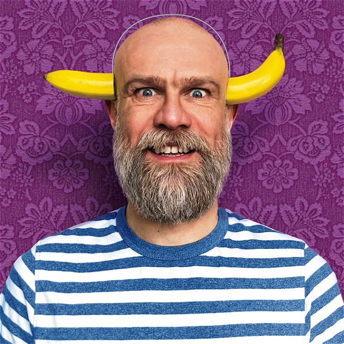 48 year old comedian with the mental age of a 10 year old. He has a bushy beard and banana sticking out of his head.