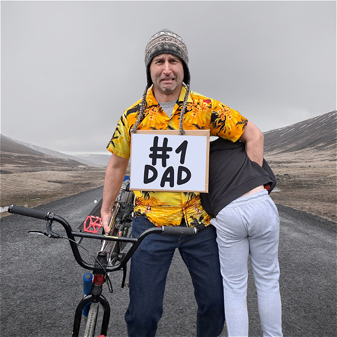 Desperate looking manholding a bike in one hand with a child under his other hand, standing in the middle of no where.