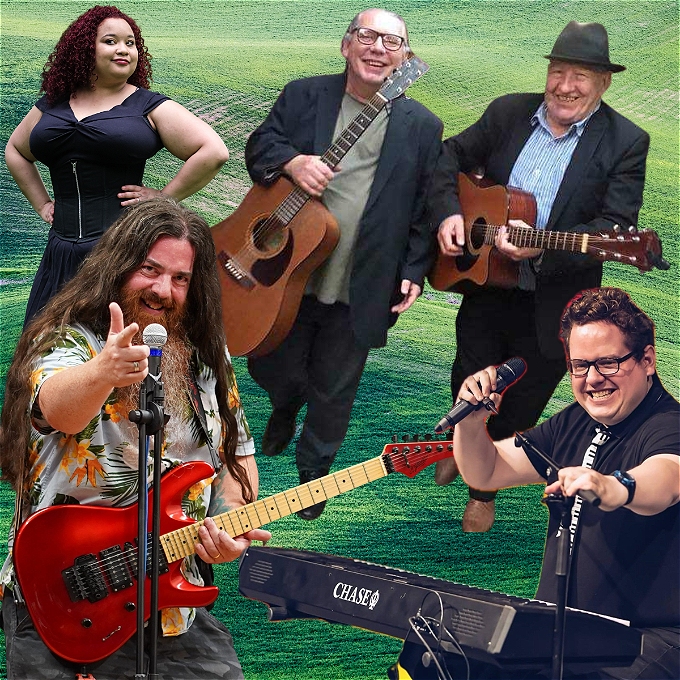 5 musical comedians. In the foreground is a white male comedian with long brown hair and beard. He is holding a red electric guitar with one hand on it's neck. The other hand is pointing at the viewer.. Next to him a white non-binary person plays the electric keyboard, he is holding a microphone. Behind him are two older gentlemen in suits, holding acoustic guitars. In the background is a young black female singer, in a black dress. She has long curly brown hair and is smiling at the viewer. She has her arms on her waist. The background is green grass.