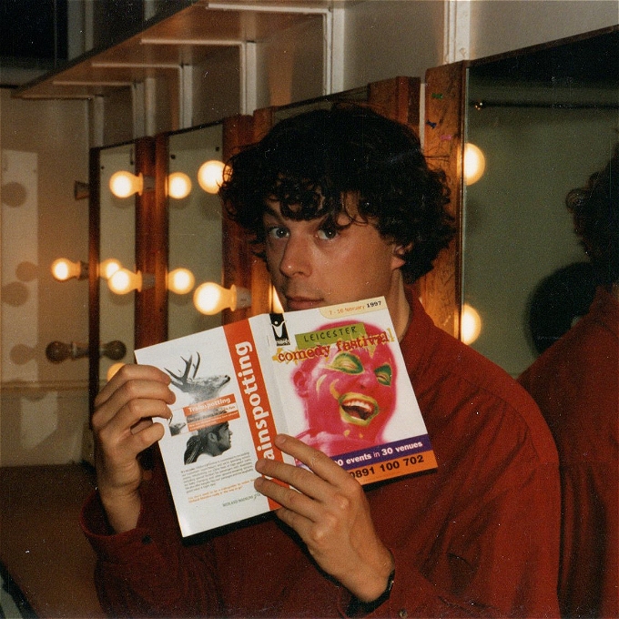 A vintage photograph of a male comedian hidden behind Leicester Comedy Festival 1997 programme.