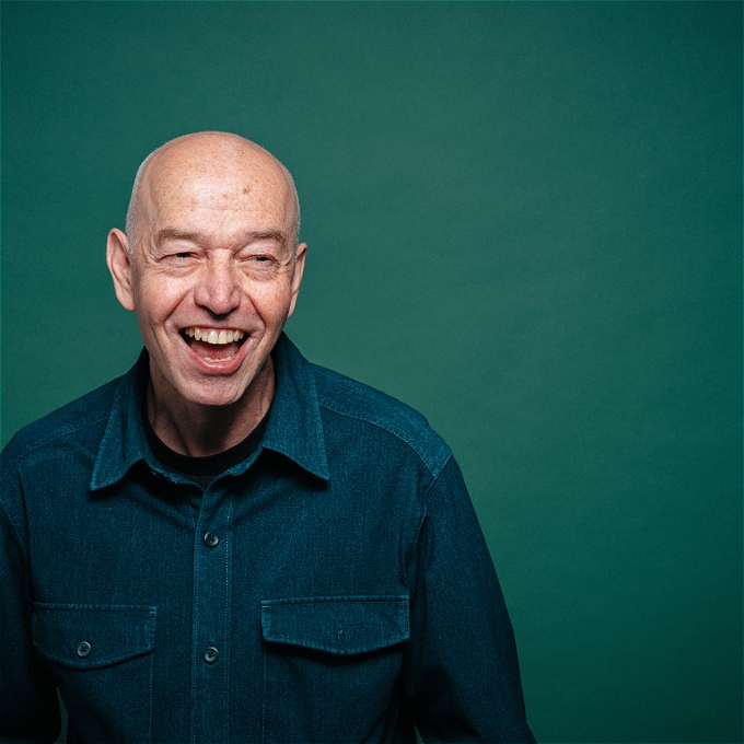 Balding, hideously ugly, middle-aged man laughing for no reason.