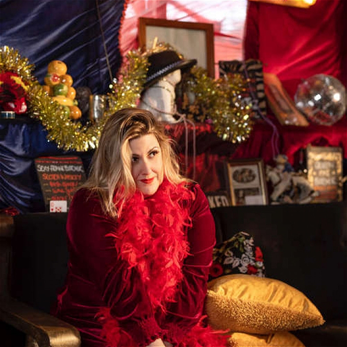 Girl in feather boa sits gazing into distance