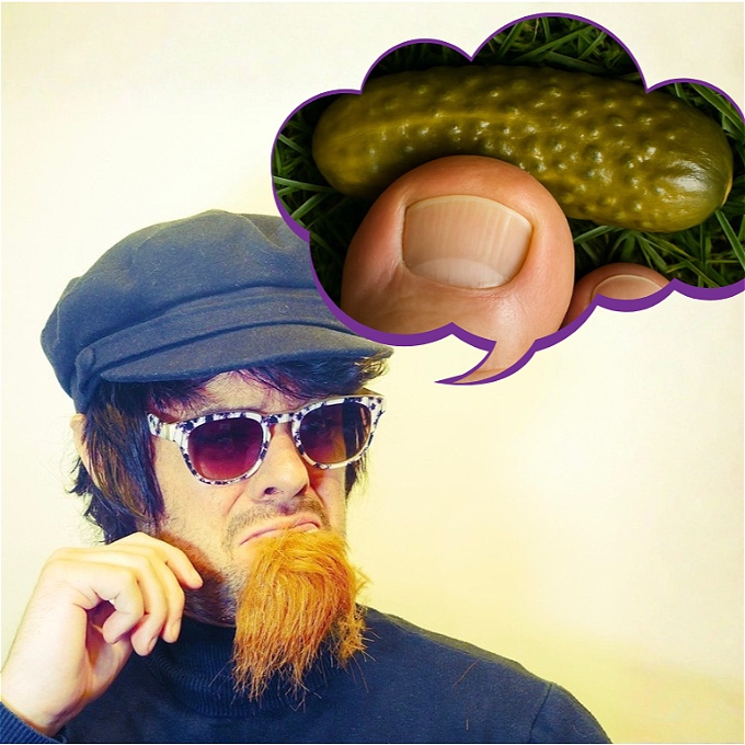 Man in a hat, glasses and ginger goatee thinking about a Big toe pressing down on a gherkin