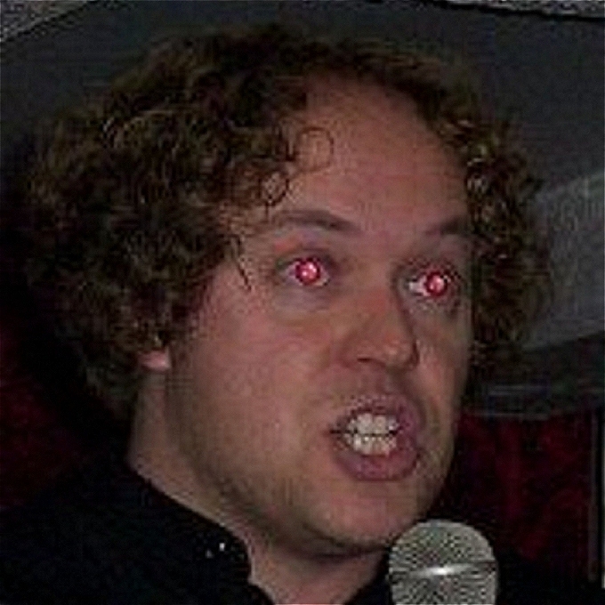 Curly haired Ben holding mic and looking slightly demonic with red eye