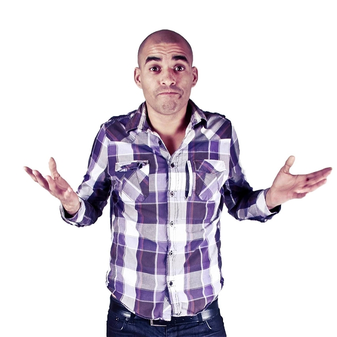 Mixed race male comedian shrugging his shoulders in checked shirt