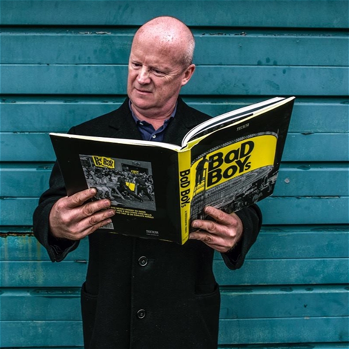 A gangster style character holding a book called 