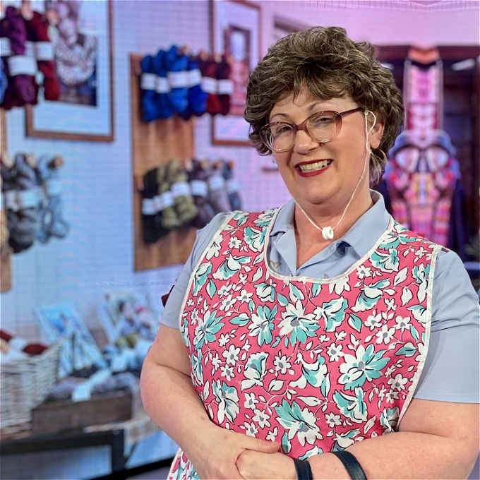 Female comedian and crafter Carol standing smiling in front of knitting