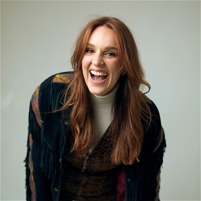 Smiling open mouthed Katie Norris leans forward towards the camera