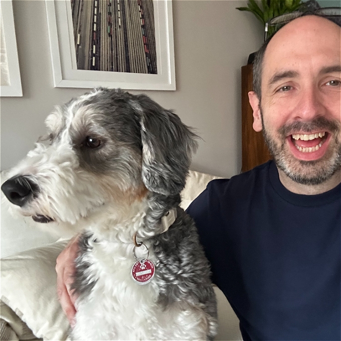 A handsome man smiling sat next to a dog