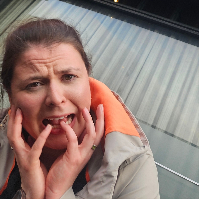 Female comedian pulling a fake scared face against a grey background