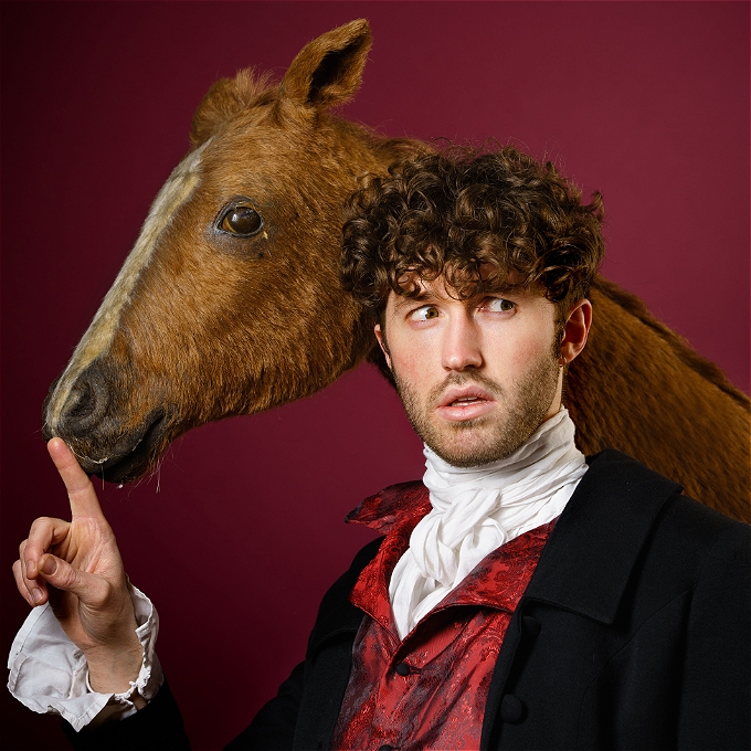 Man dressed as Regency highwayman shushes a horse while looking off into the distance