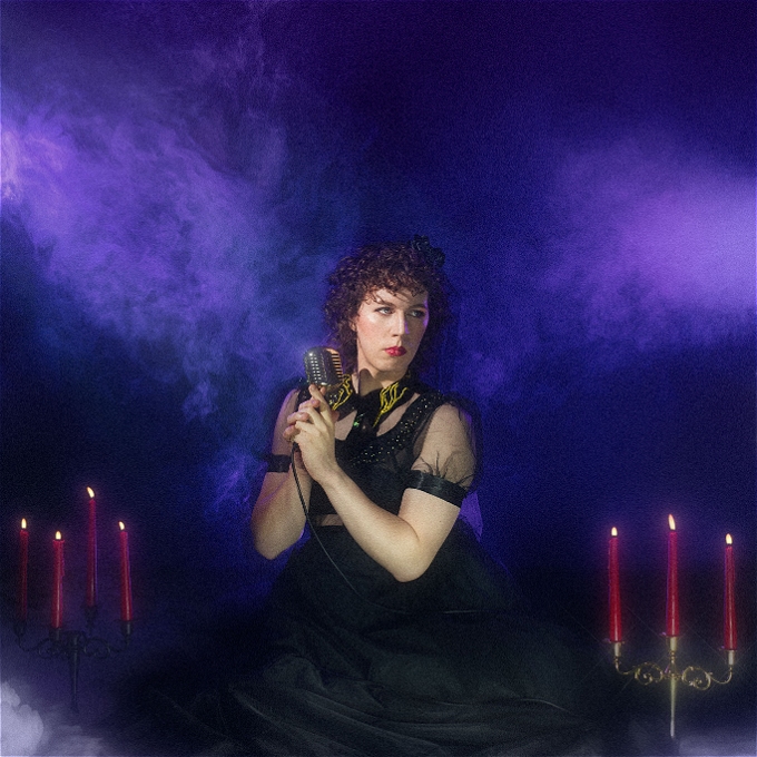 holding a vintage microphone and surrounded by wisps of smoke and bracketed by 2 Candelabra, a sultry Sam Nicoresti looks off to the side of the camera