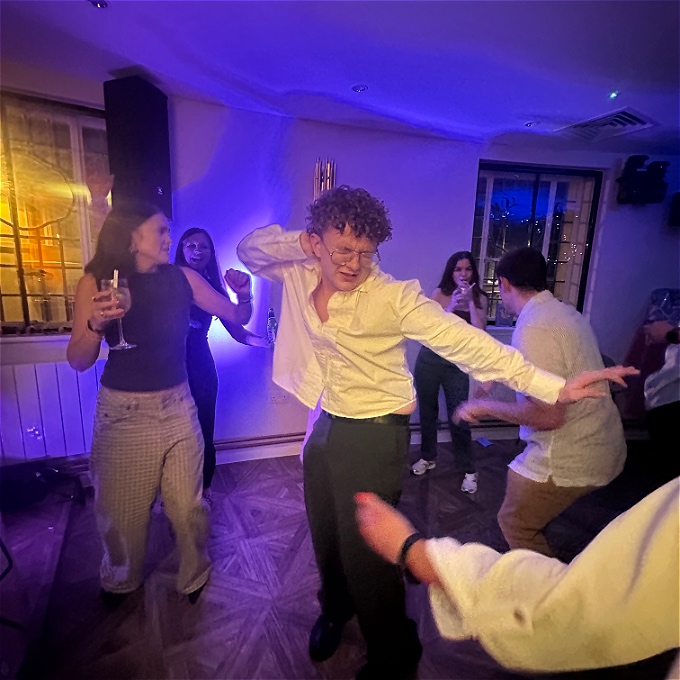 Male presenting comedian dancing energetically in a crowd of onlookers