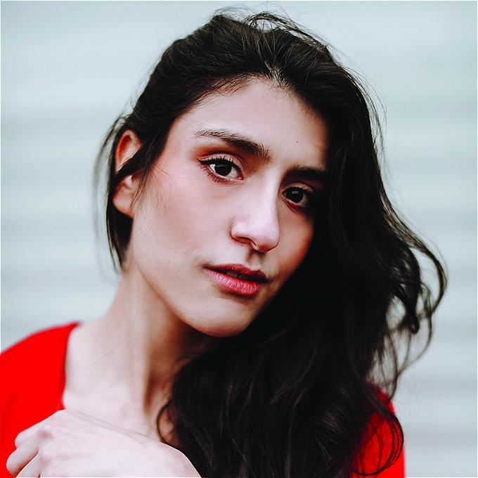 Celya AB's long brown hair is swept over one shoulder