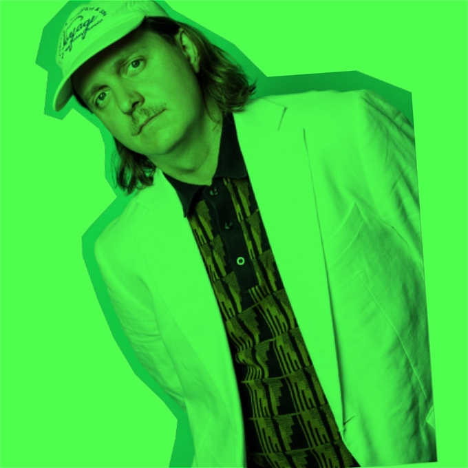 Joey Page wearing a casual shirt, suit and cap, with a green filter on the image