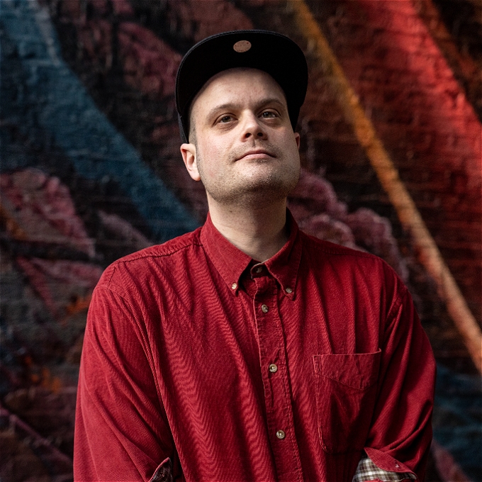 Male comedian with a hat and red shirt