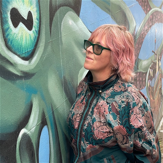 A woman in leopard print roars at the camera bestride a heap of cuddly toy animals.