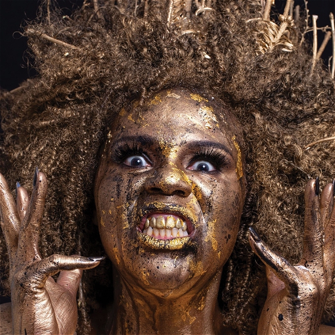 Comedian Desiree Burch is painted gold and baring her teeth
