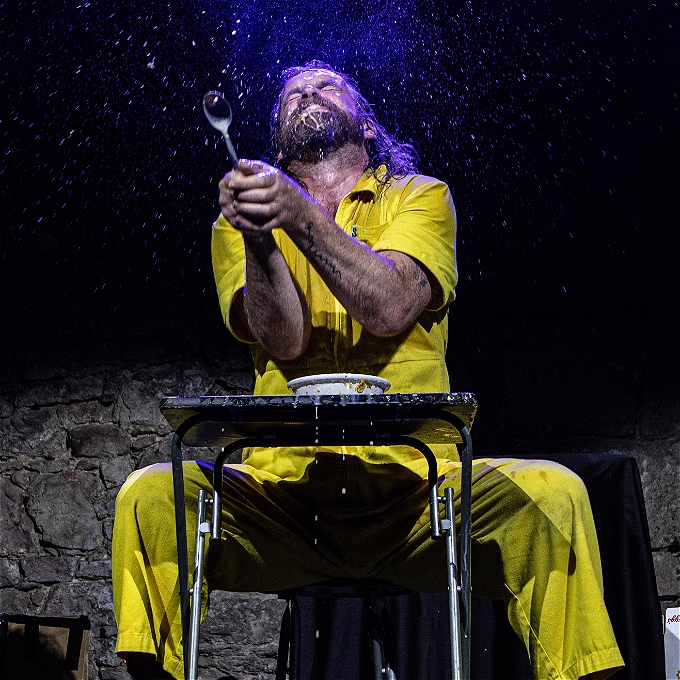 Sweaty comedian with beard spitting cornflakes into the audience