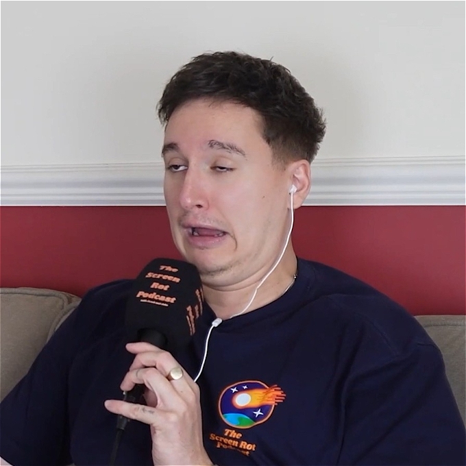 Jacob Hawley holding a mic while recording a podcast pulls an awkward face.