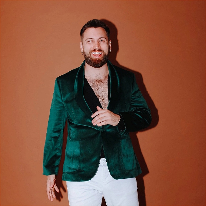 Male comedian in green velvet jacket laughing