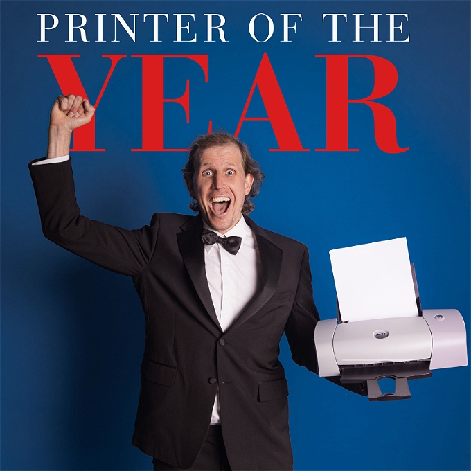 Male in a dinner jacket holding a desktop printer like an award